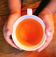 hands holding a cup of black tea